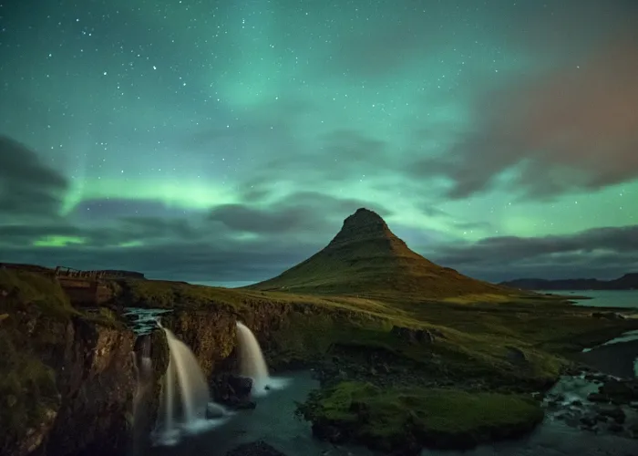 The glowing green curtains of the Aurora Borealis arching over a dark sea