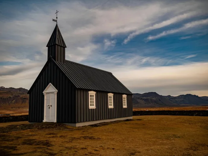 A single solitary wooden church standing against a vast mountain backdrop